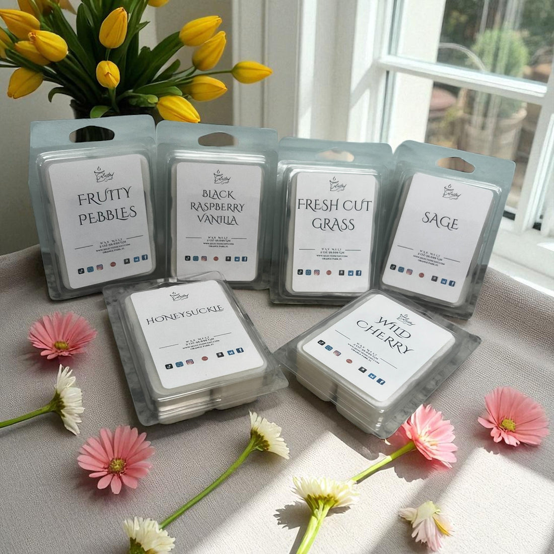 Wax melts for home fragrance in various scents including fruity pebbles and wild cherry displayed with flowers near a window