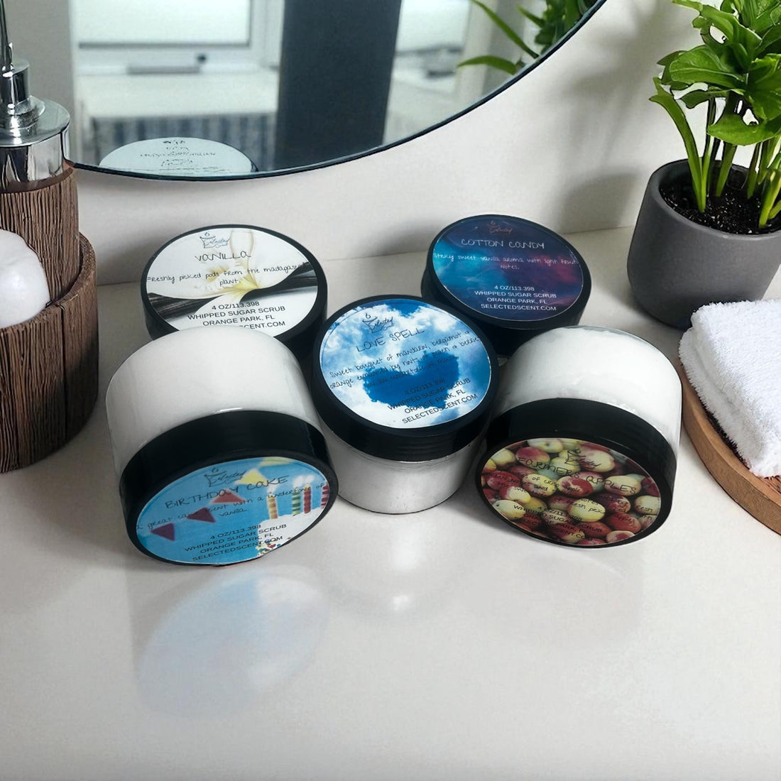 Collection of exfoliating sugar scrubs in various scented jars displayed on a bathroom counter