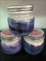 Selected Scent candles in glass jars with silver lids featuring a soft purple and blue design and A Soft Fruity Scent