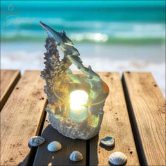 Family dolphin aromatherapy burner with glowing candle on wooden surface by the beach
