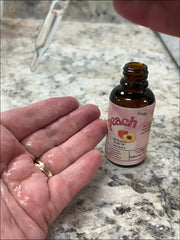 Selected Scent peach oil dropper applying hydrating and protecting facial oil on hand