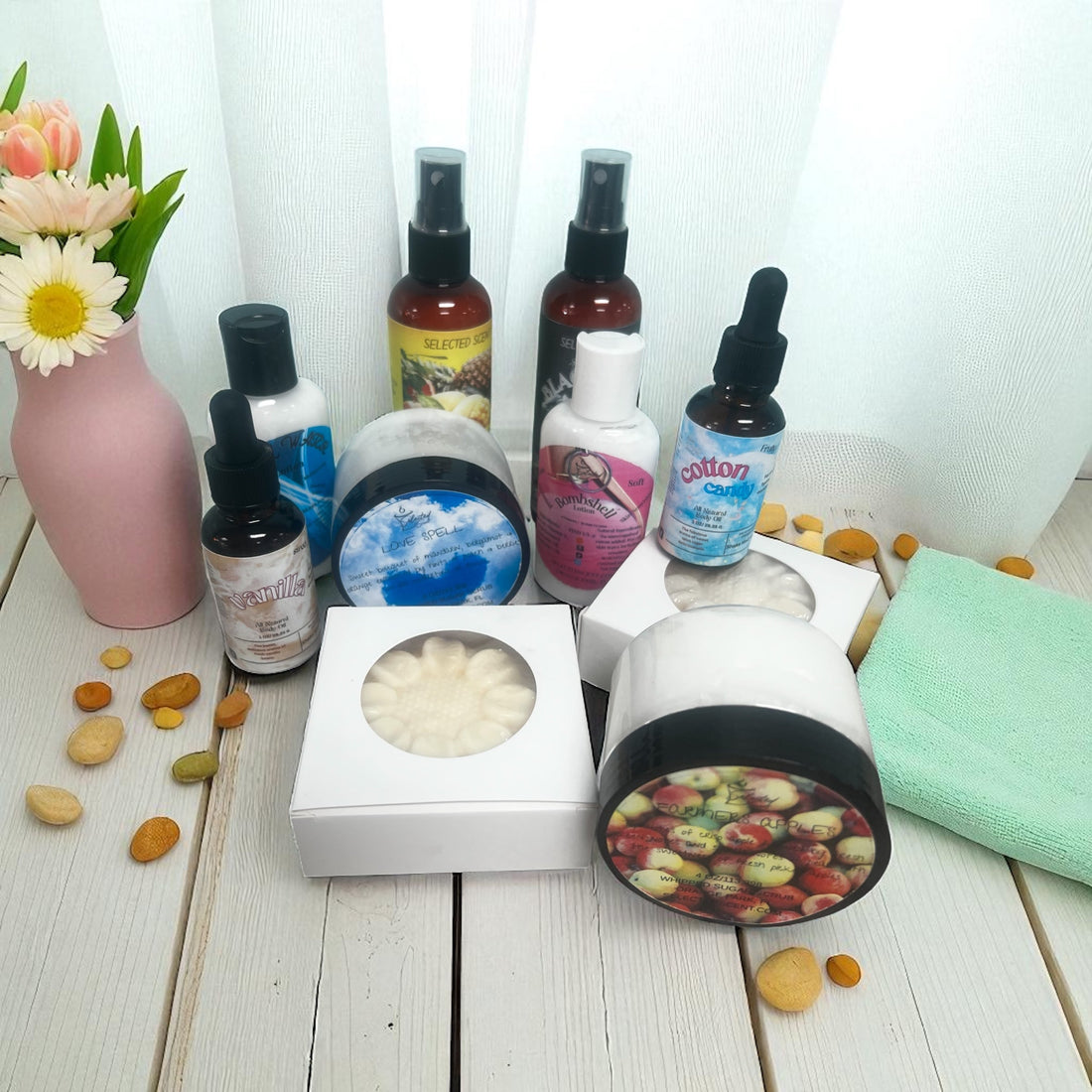 Collection of long lasting fragrance body care products including lotions, sprays, and creams on white wooden surface