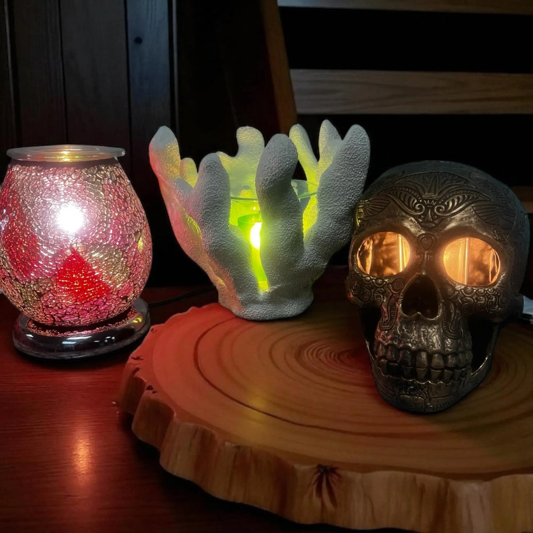 Collection of adjustable oil and wax warmers including a glass, coral-shaped, and skull design on a wooden surface