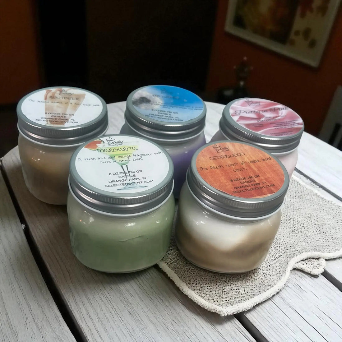 Collection of handmade 8oz candles for home in various scents and colors displayed on a wooden surface