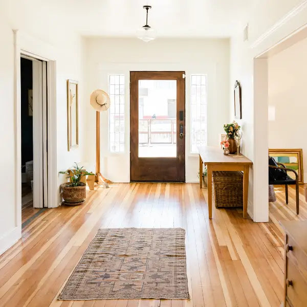 Bright entryway featuring wooden floors and furniture with Decorative Home Accents including plants and art