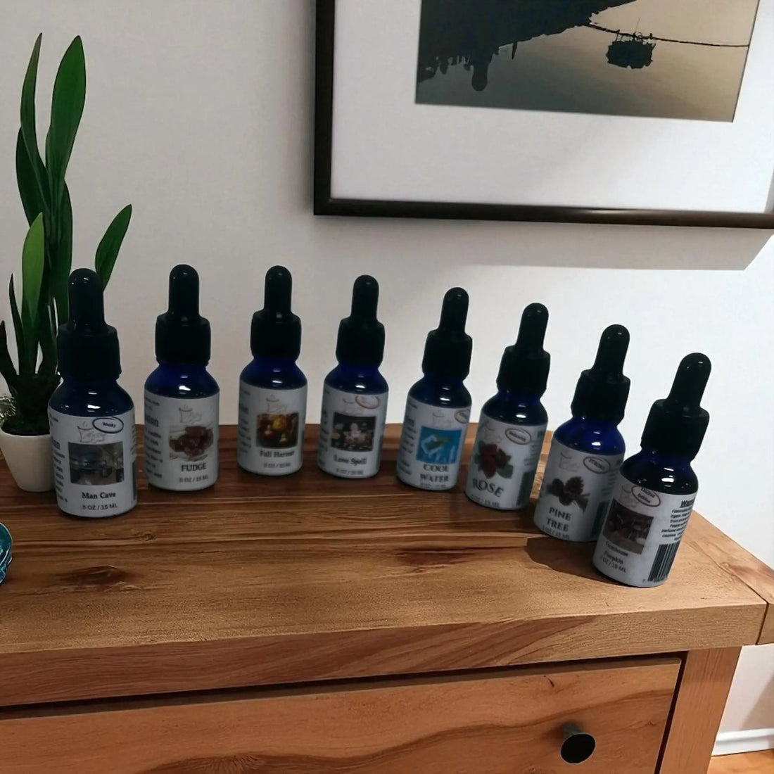 Collection of long lasting fragrance oils in dropper bottles displayed on wooden surface with green plant in background