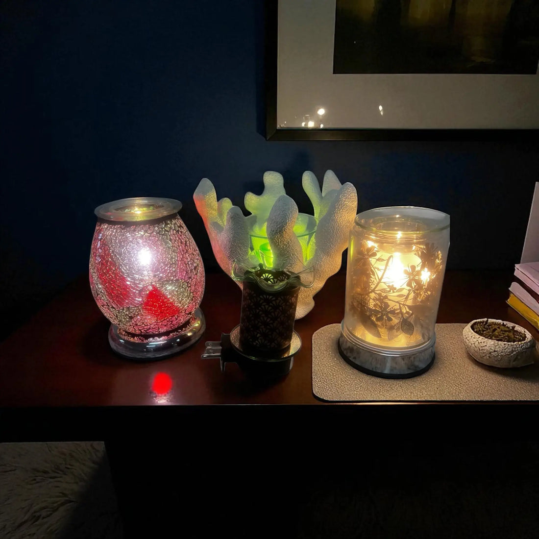 Wax accessories for home fragrance including decorative candle warmers glowing on a dark wooden table