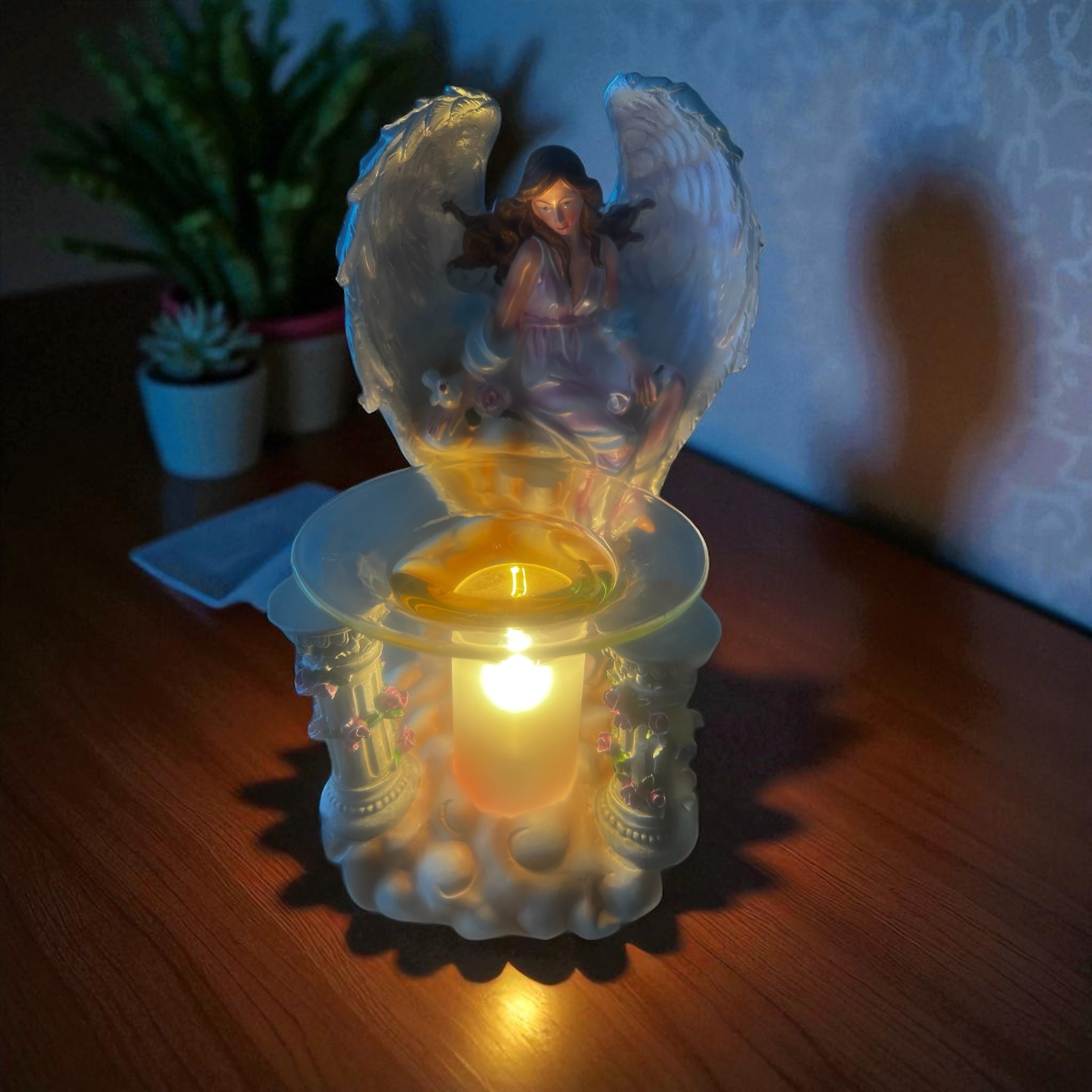 Selected Scent electric decorative warmer with angel design glowing warmly on wooden surface