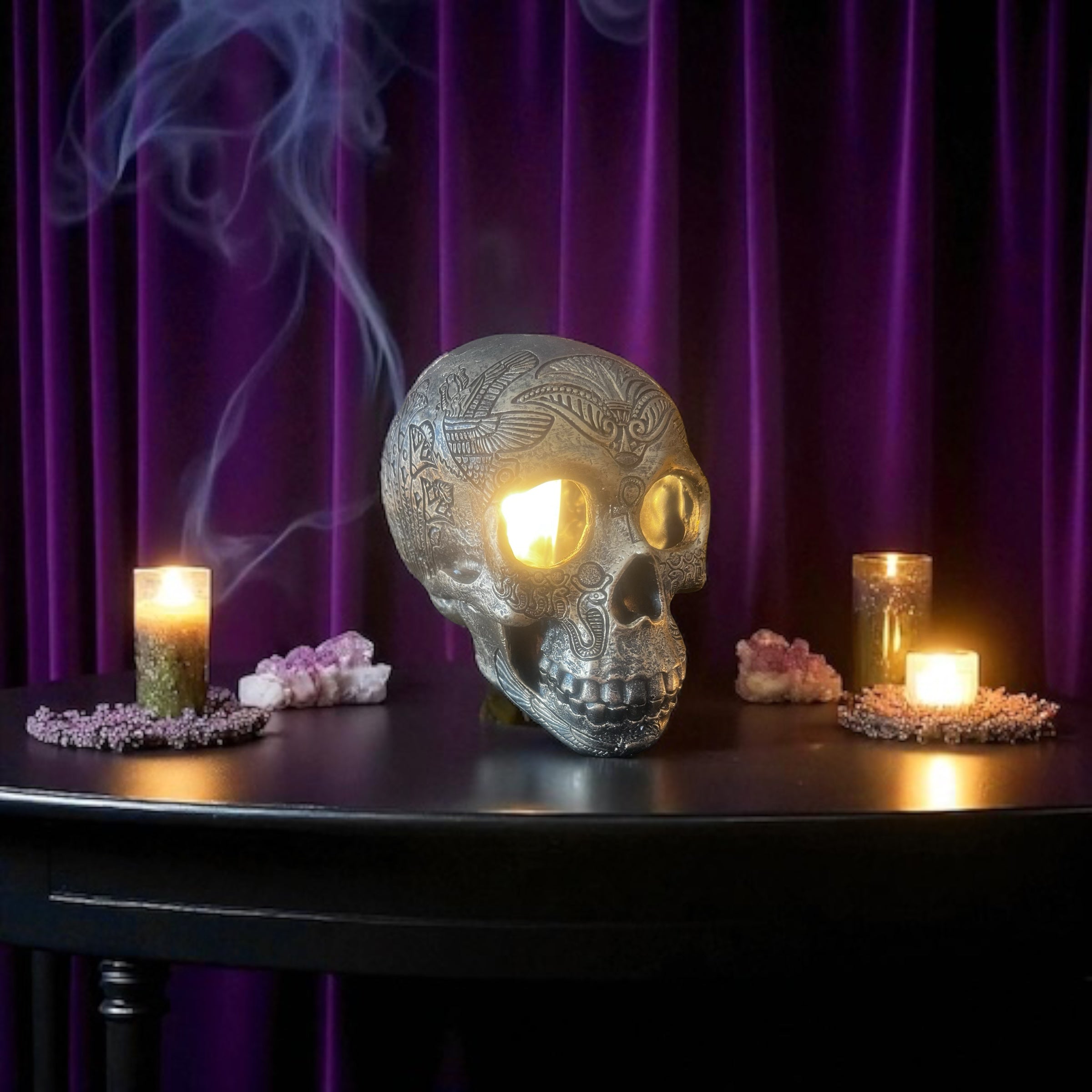 Selected Scent electric decorative warmer shaped like a detailed skull with glowing eyes on a black table with candles