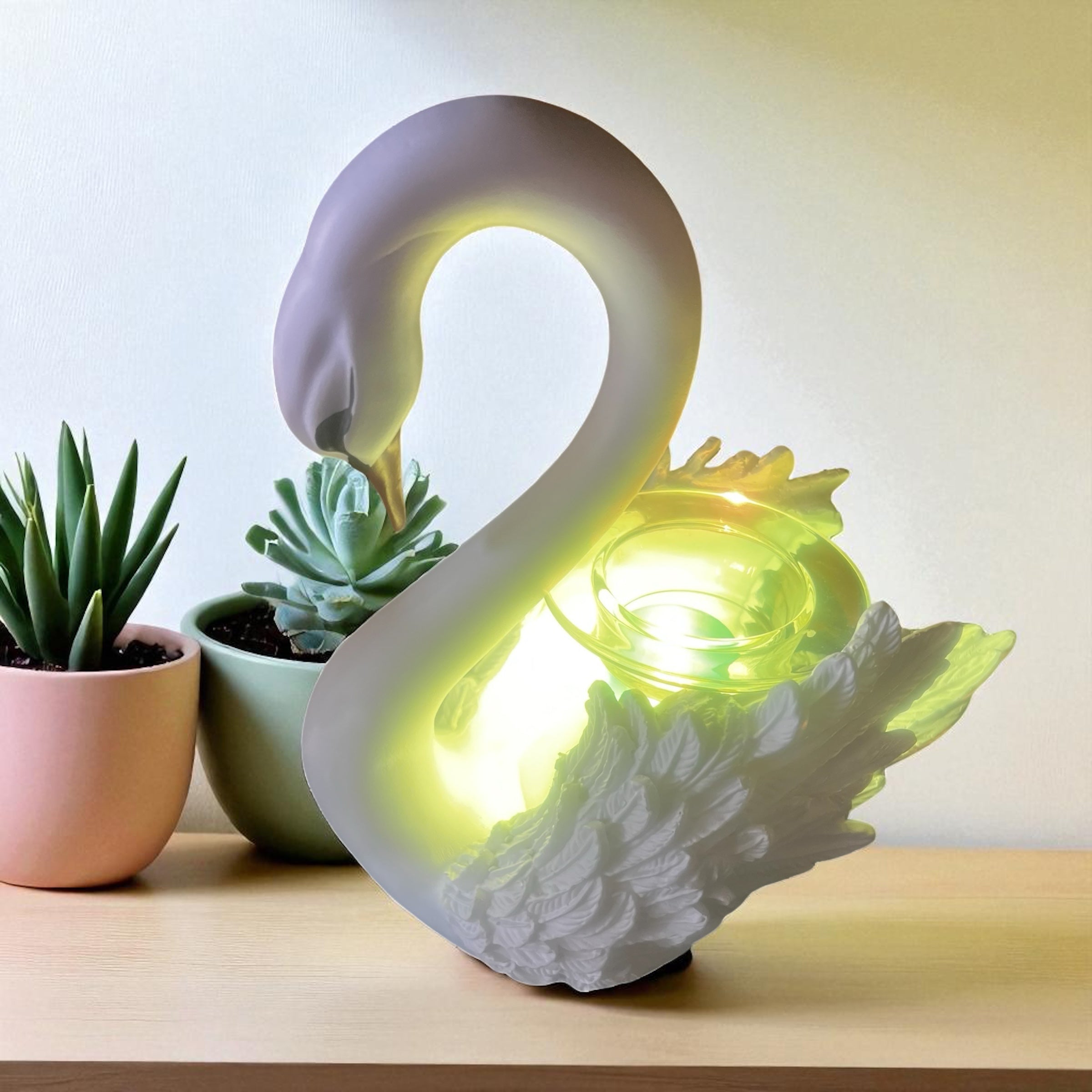 Selected Scent Electric Decorative Warmer shaped like a white swan glowing on wooden surface with small potted succulents