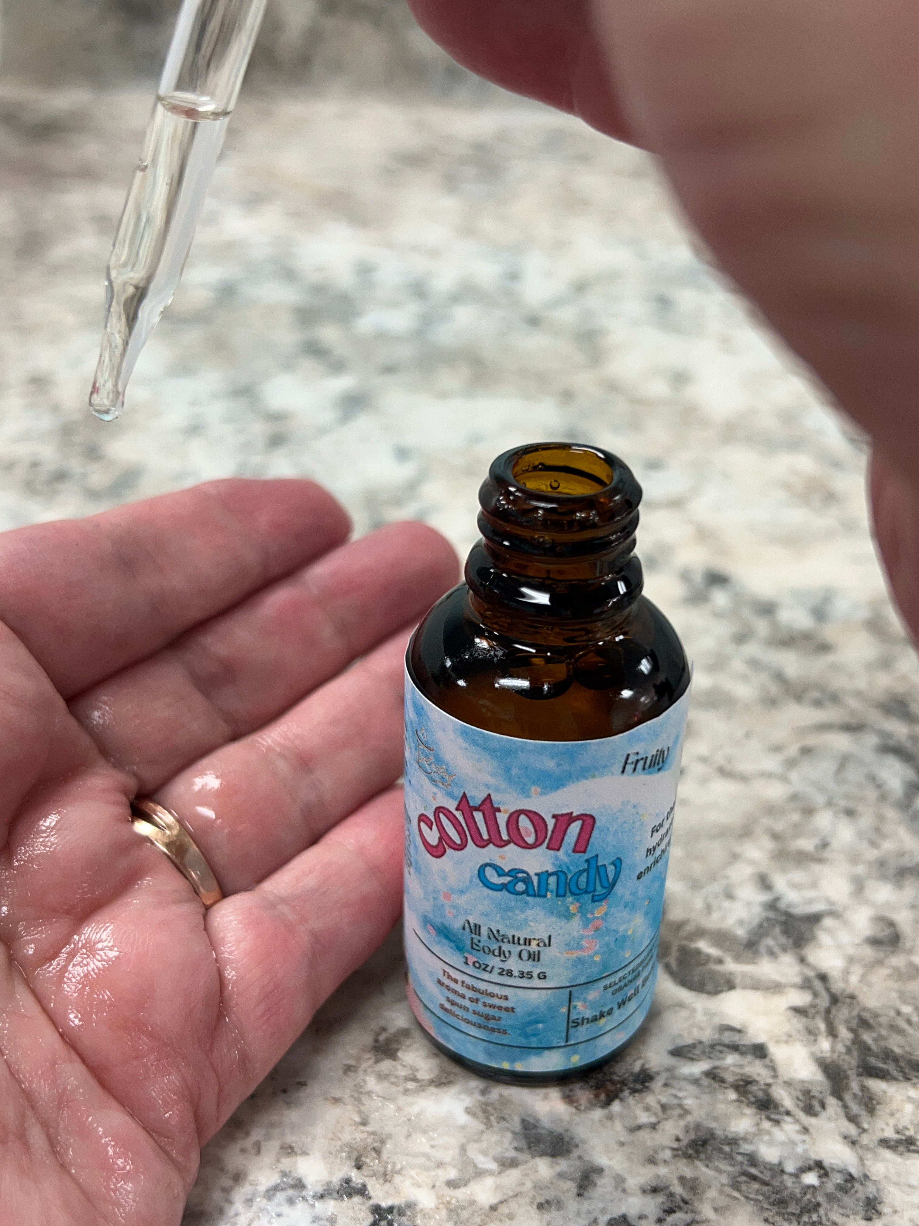 Selected Scent Cotton Candy natural body oil being applied with dropper for hydrating and protecting skin
