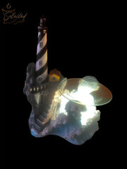 Selected Scent Electric Decorative Warmer shaped like a lighthouse with a glowing light and detailed rocky base