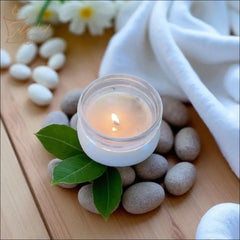 Selected Scent scented candle with mango butter and vitamin E surrounded by green leaves and smooth stones