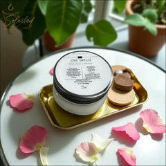 Selected Scent Love Spells massage candle with mango butter and vitamin E on gold tray with pink flower petals