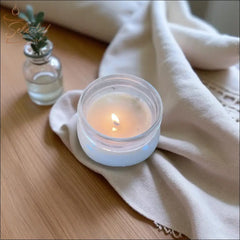 Selected Scent scented candle with mango butter burning next to a small glass vase on a wooden surface