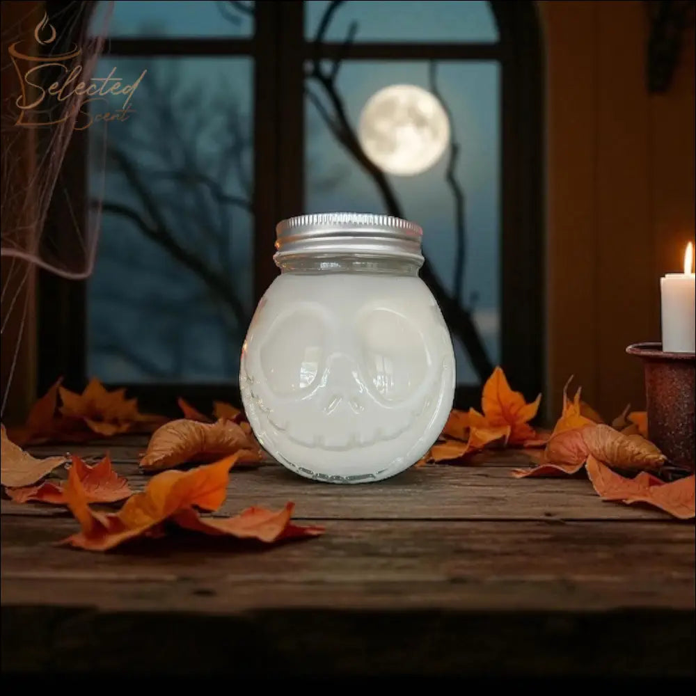 Selected Scent 16 oz pumpkin spice candle cup in skull-shaped glass jar on wooden table with autumn leaves