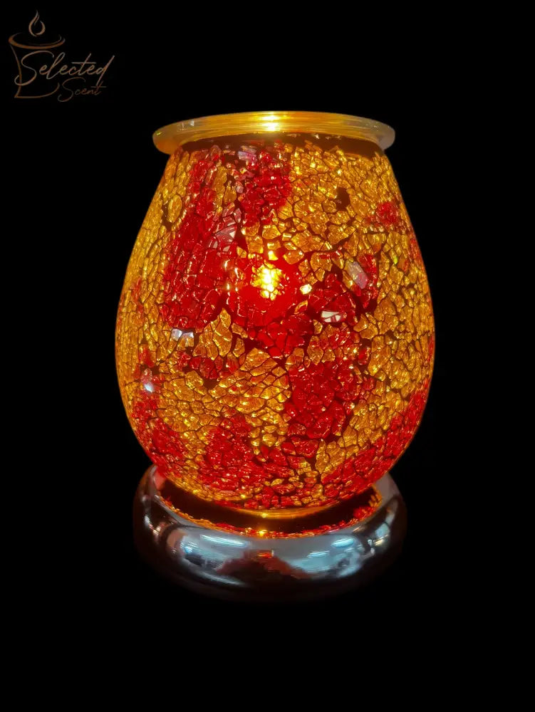 Selected Scent electric decorative warmer with red and gold mosaic glass design lit on black background