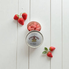 Selected Scent strawberry wax melts for fragrance in a round container with fresh strawberries on white wooden background
