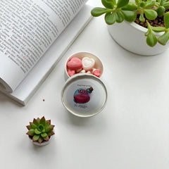 Selected Scent love spell wax melts in white tin with pink heart shaped melts beside book and succulents