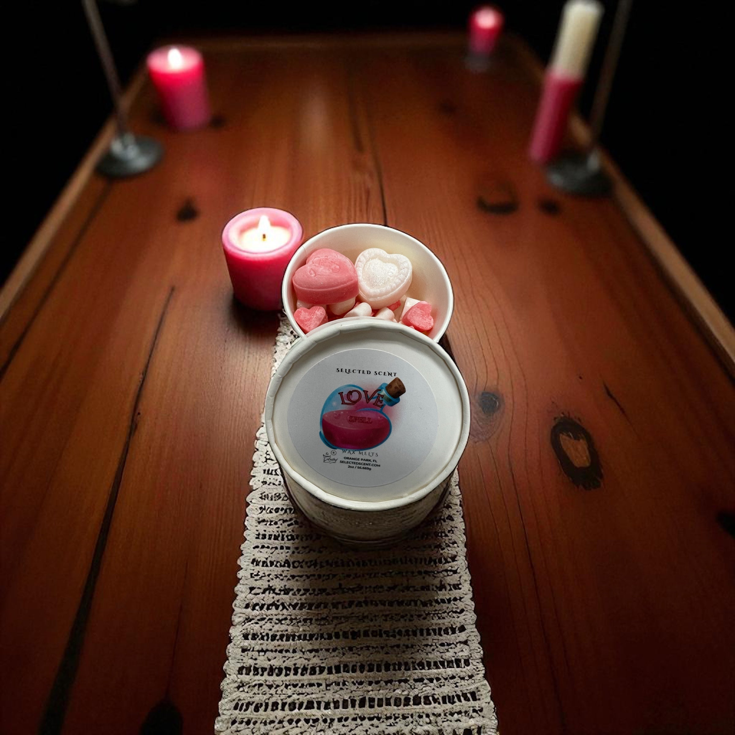 Selected Scent love spell wax melts in white tin with pink and white heart shaped melts on wooden table with candles