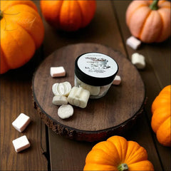 Jar of vanilla pumpkin marshmallow wax melts on a wooden slab surrounded by small decorative pumpkins